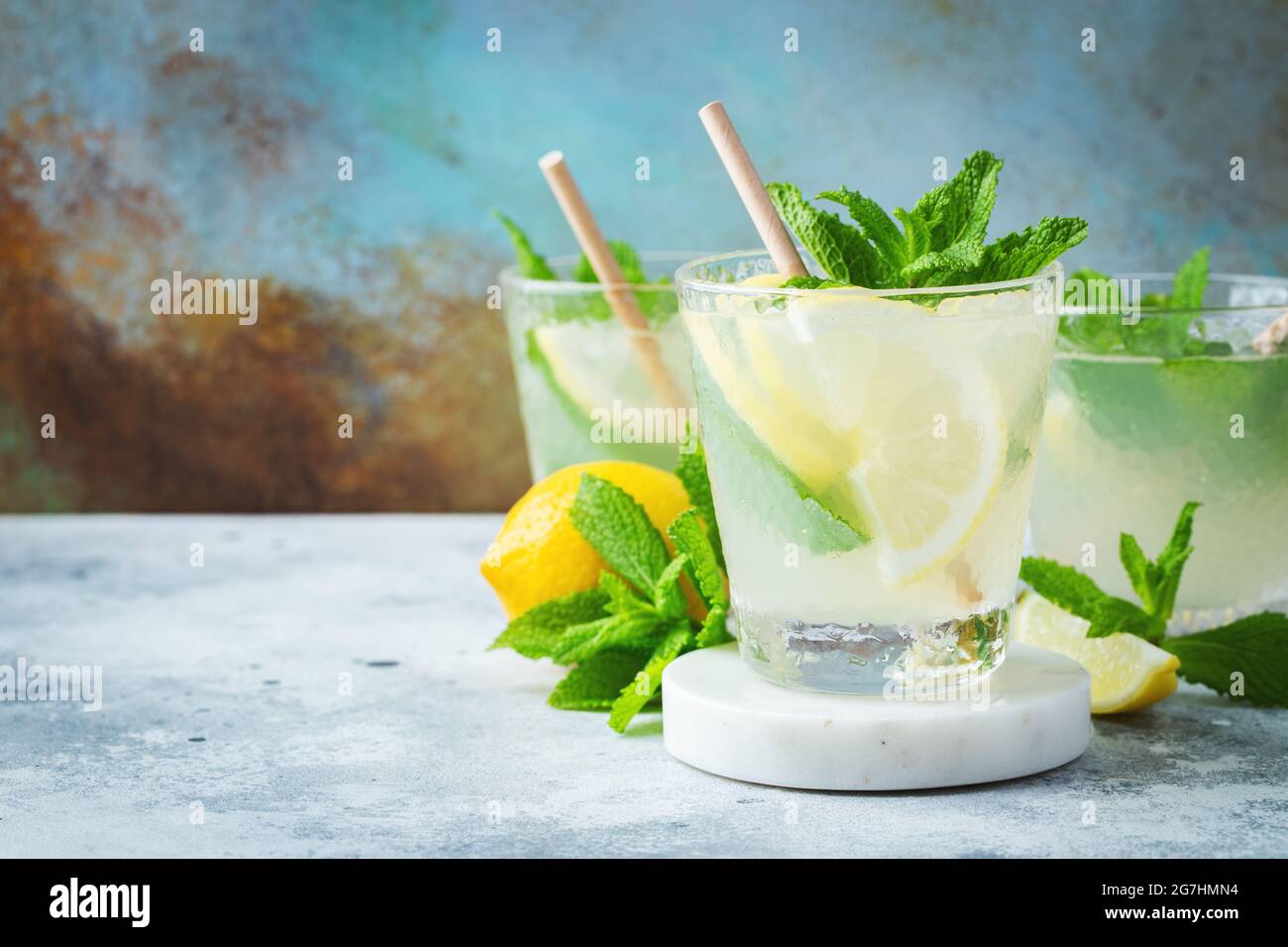 Deux verres avec limonade ou cocktail mojito avec citron et menthe, boisson rafraîchissante froide ou boisson avec glace sur fond bleu rustique. Copier l'espace Banque D'Images
