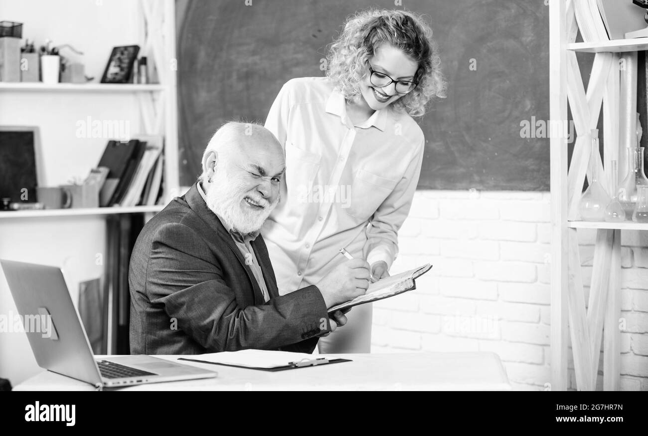 Étudiant interrogeant le professeur sur la tâche. Résolution des tâches mathématiques. Concept d'éducation scolaire. Vérifier les devoirs. Éducateur et étudiant regardant le livre. Explication Banque D'Images