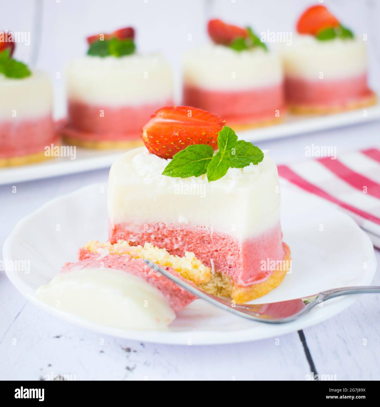 Mini-cheesecakes à la noix de coco et aux fraises. Monoportions de dessert d'été avec noix de coco, chocolat blanc et fraises fraîches. Banque D'Images