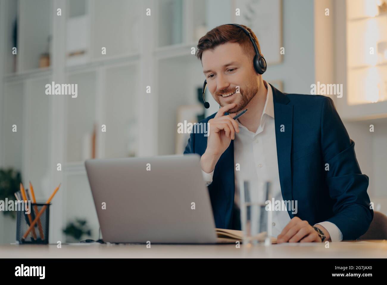 Un opérateur professionnel travaillant dans un centre d'appels utilise un casque et un ordinateur portable lors de conversations vidéo ou d'événements de webcam virtuelle porte des poses de vêtements formels Banque D'Images