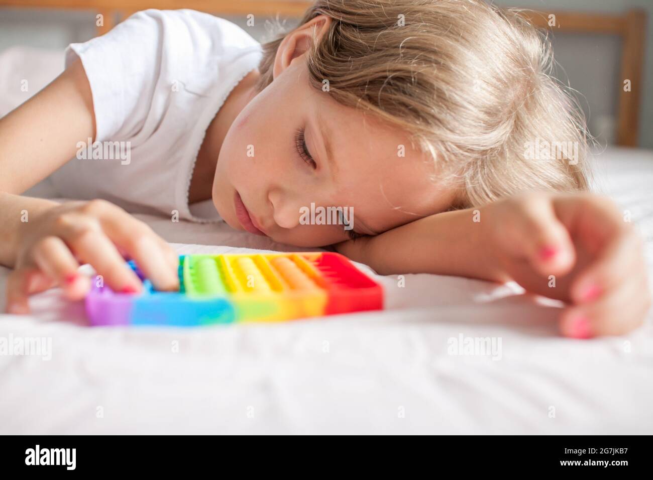 Petite fille joue avec le jouet sensoriel branché pop. La jeune fille appuie sur des bulles de silicone souple arc-en-ciel colorées. Soulagement du stress et de l'anxiété. Banque D'Images