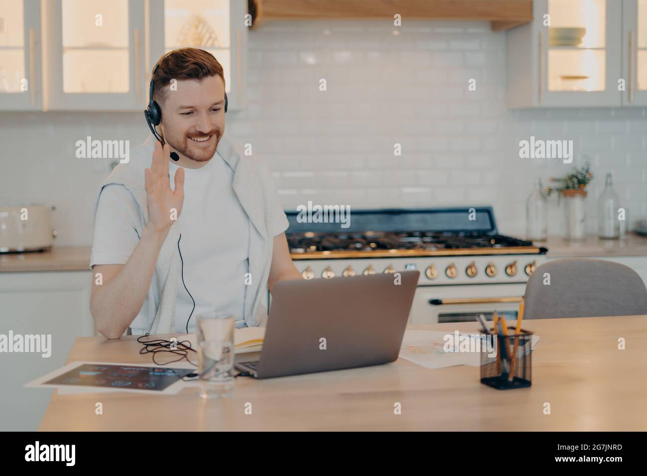 Un jeune homme heureux qui donne des leçons lors de la formation en ligne sur un ordinateur portable à la maison Banque D'Images