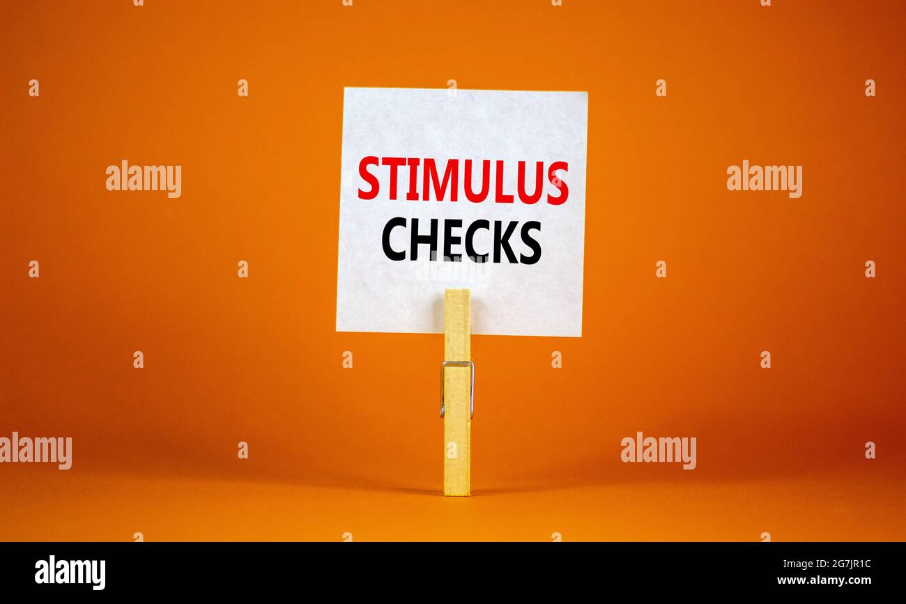 Symbole de contrôle de stimulus. Livre blanc avec les mots « Stimulus cheques », clip sur la corde à linge en bois. Magnifique arrière-plan orange. Contrôles des affaires et des mesures de relance Banque D'Images