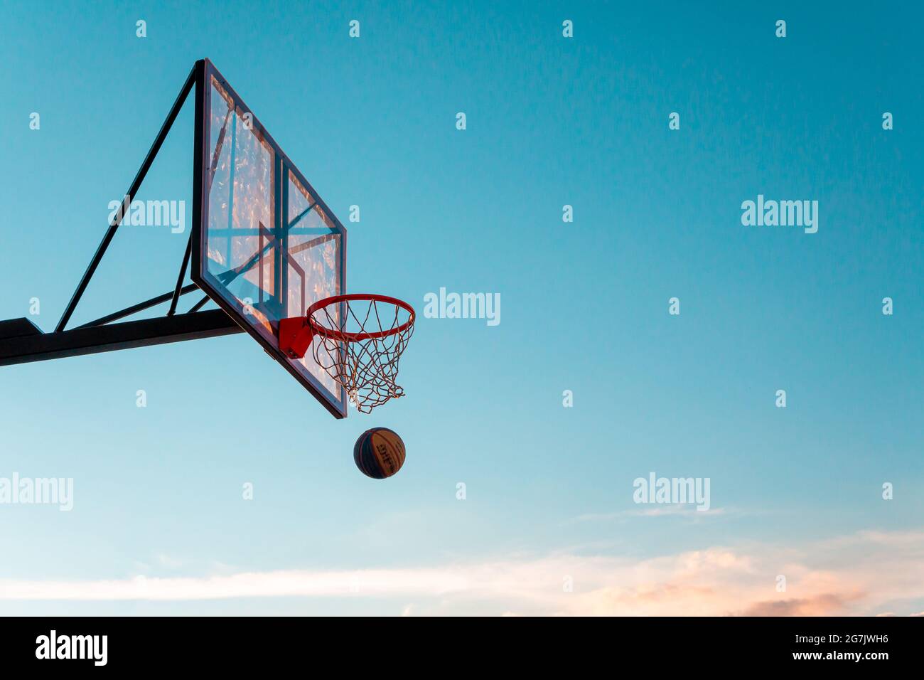 Kazan, Russie - 12 septembre 2020 : un panier de basket-ball avec une balle sur fond bleu ciel. Blindage de basket-ball en plastique transparent sur le bas extérieur Banque D'Images