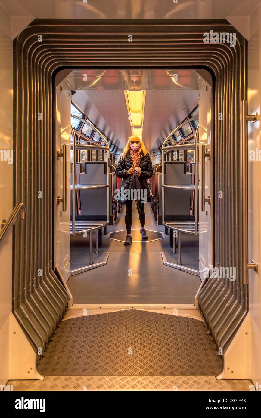 Femme blonde portant des lunettes de soleil et un masque facial debout dans la voiture du train et regardant la caméra. Banque D'Images