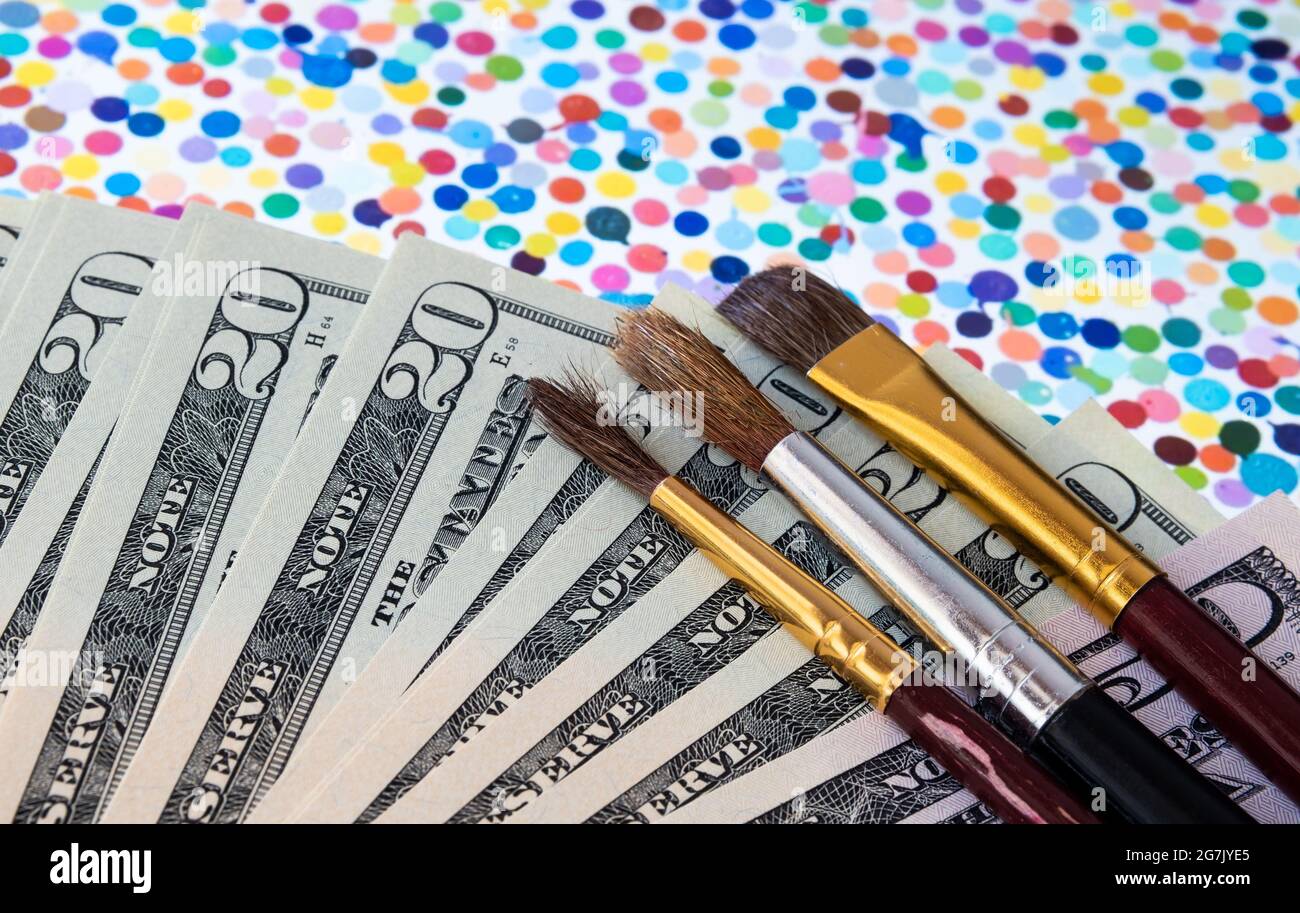 De l'argent et des pinceaux placés sur le dessus de la peinture de spot vu sur iPad flou. L'art numérique de Damien Hirst qui s'est vendu sous le nom de devise NFT. Stafford, Royaume-Uni Banque D'Images