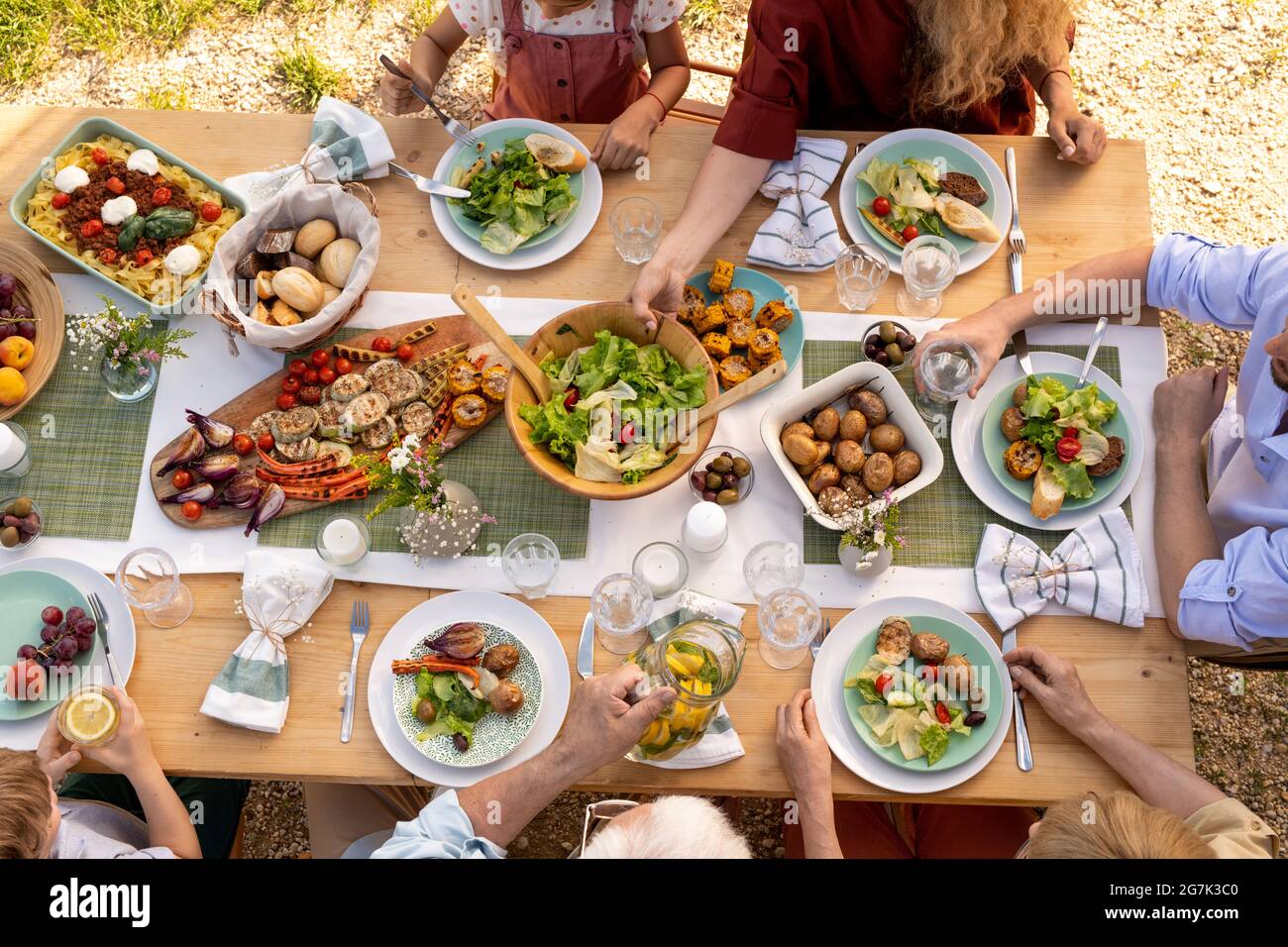 Groupe de personnes mangeant des plats délicieux à table de fête avec salade et légumes grillés, vue du dessus Banque D'Images
