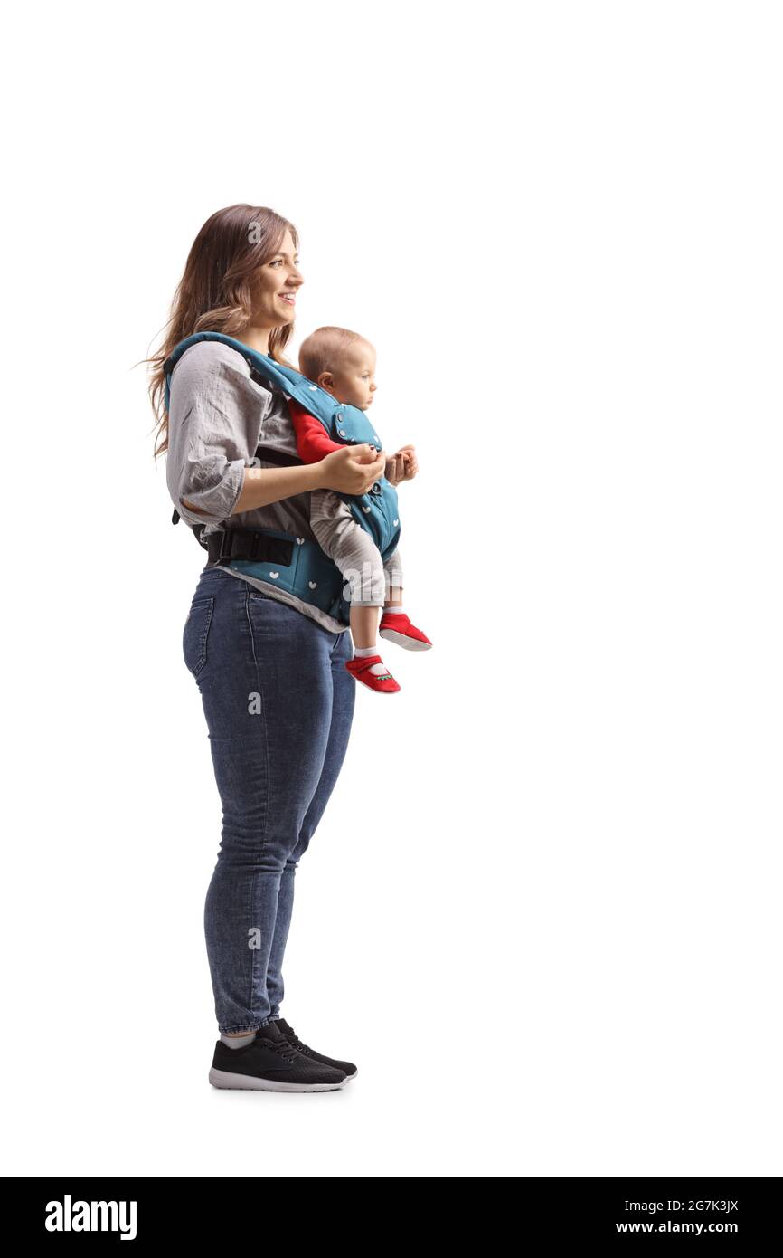 Photo de profil pleine longueur d'une mère debout avec un bébé dans un porteur isolé sur fond blanc Banque D'Images