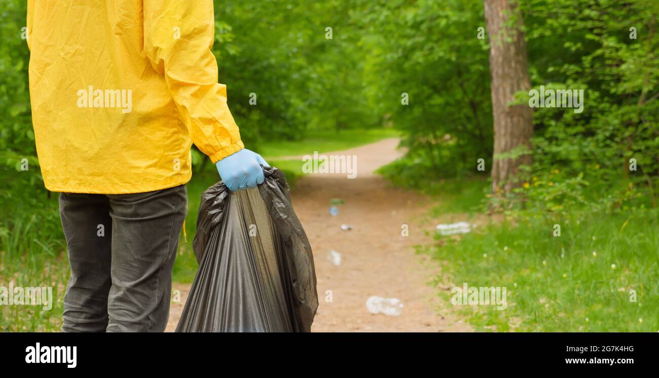 Faire du bénévolat pour nettoyer les ordures d'une forêt. Les gens se  soucient de la pollution de la terre plastique poubelle main main tenant  sac poubelle. Passez au vert. Bannière mains de