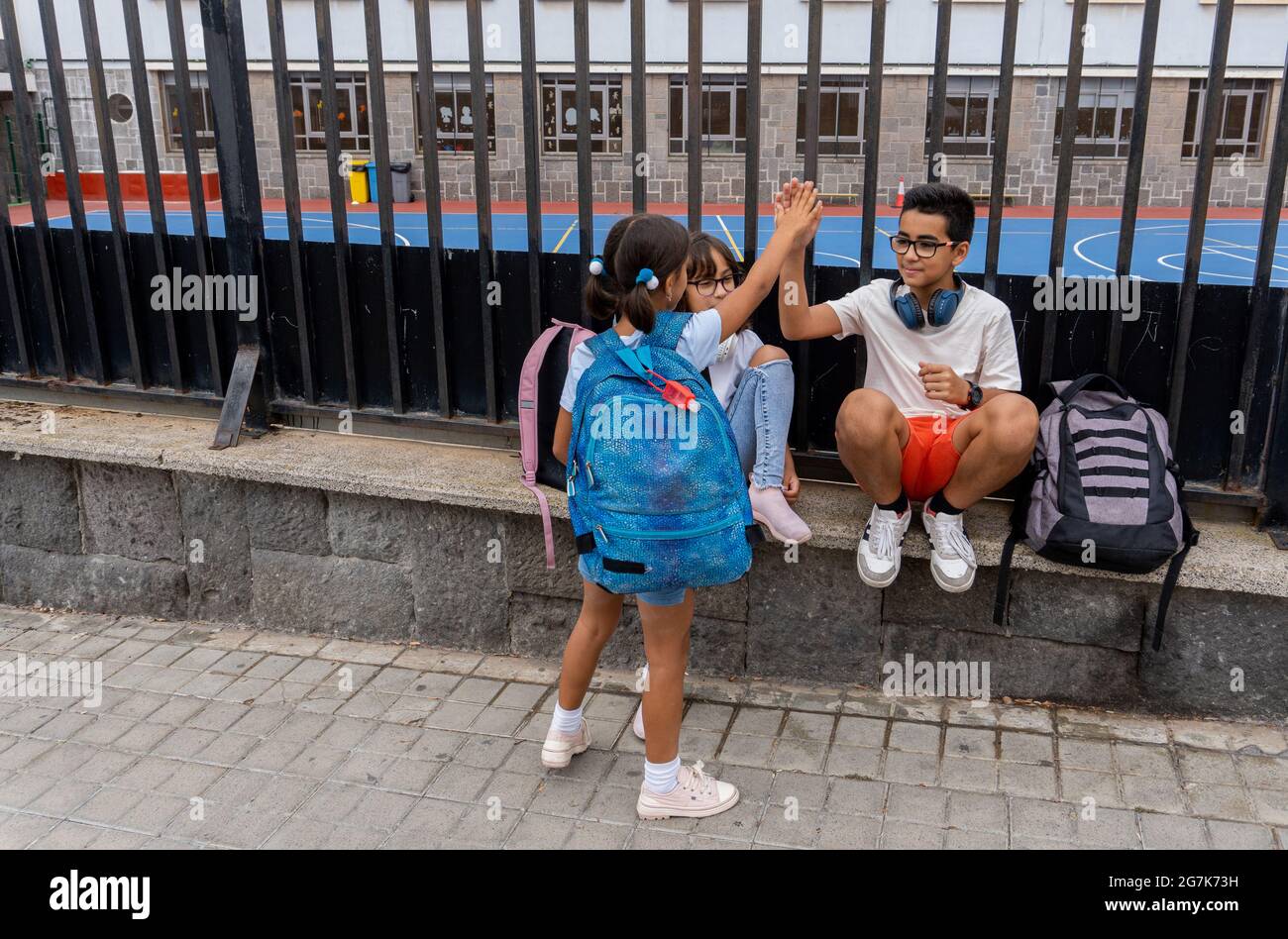 Trois enfants du Caucase saluant et parlant à la porte de l'école. Concept de retour à l'école. Banque D'Images