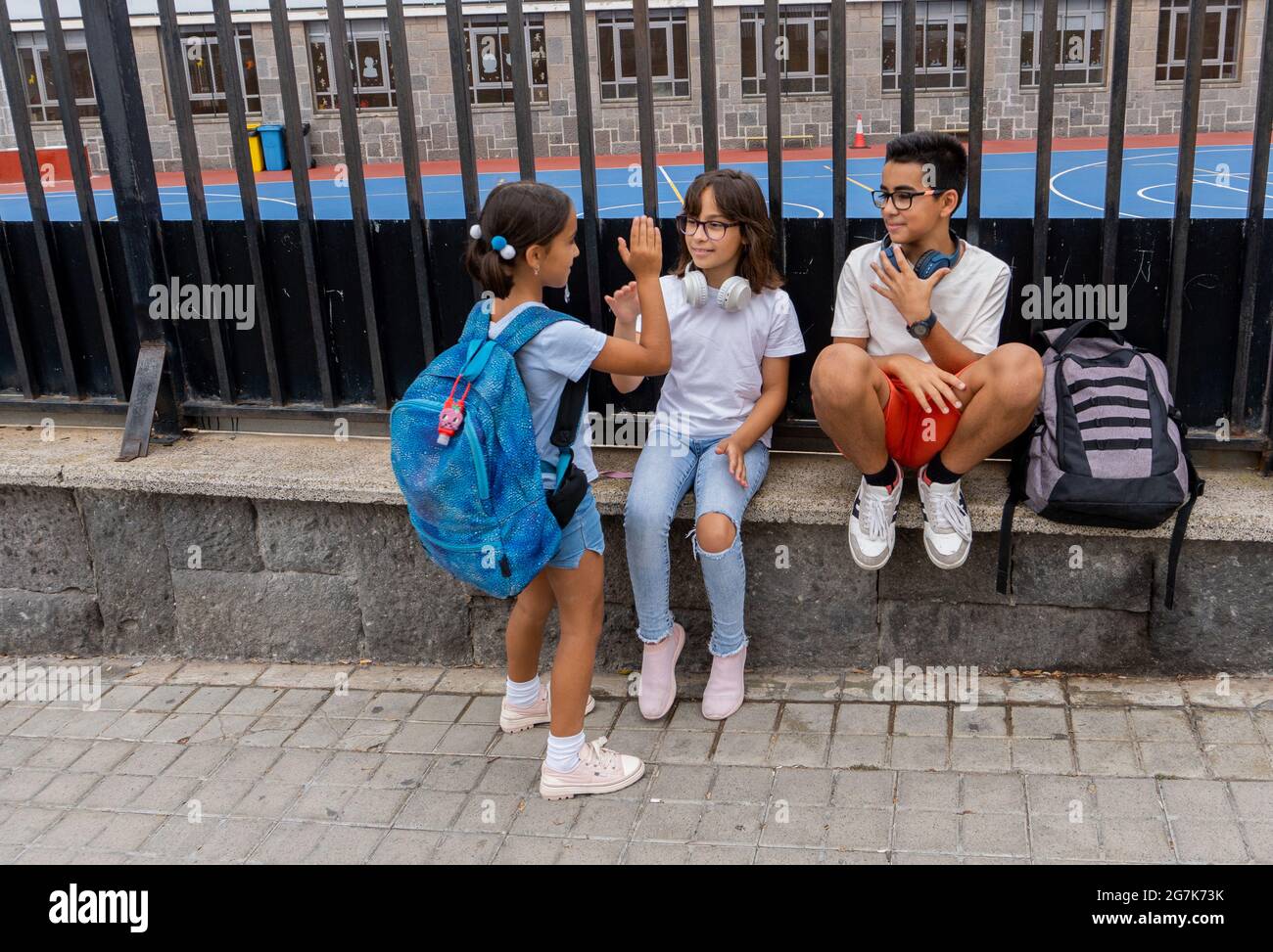 Trois enfants du Caucase saluant et parlant à la porte de l'école. Concept de retour à l'école. Banque D'Images