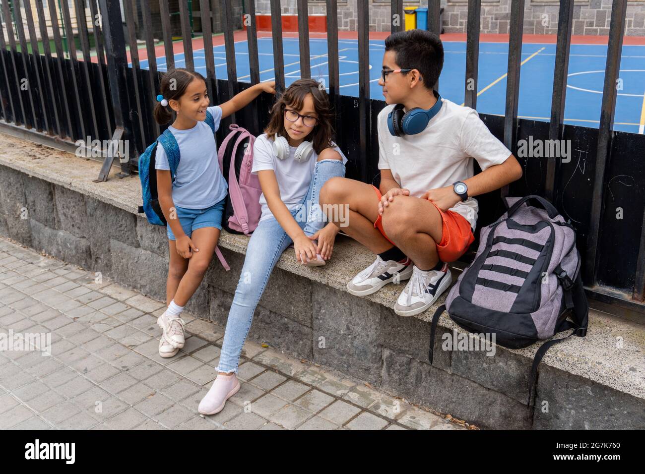 Trois enfants du Caucase saluant et parlant à la porte de l'école. Concept de retour à l'école. Banque D'Images