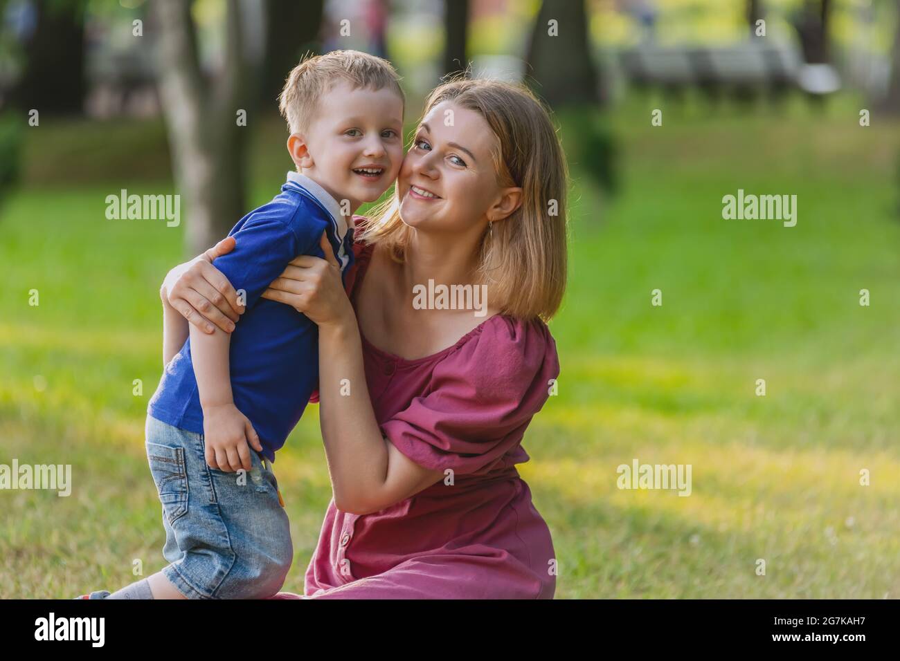 Une jeune femme marche dans le parc avec un enfant de trois ans. Banque D'Images