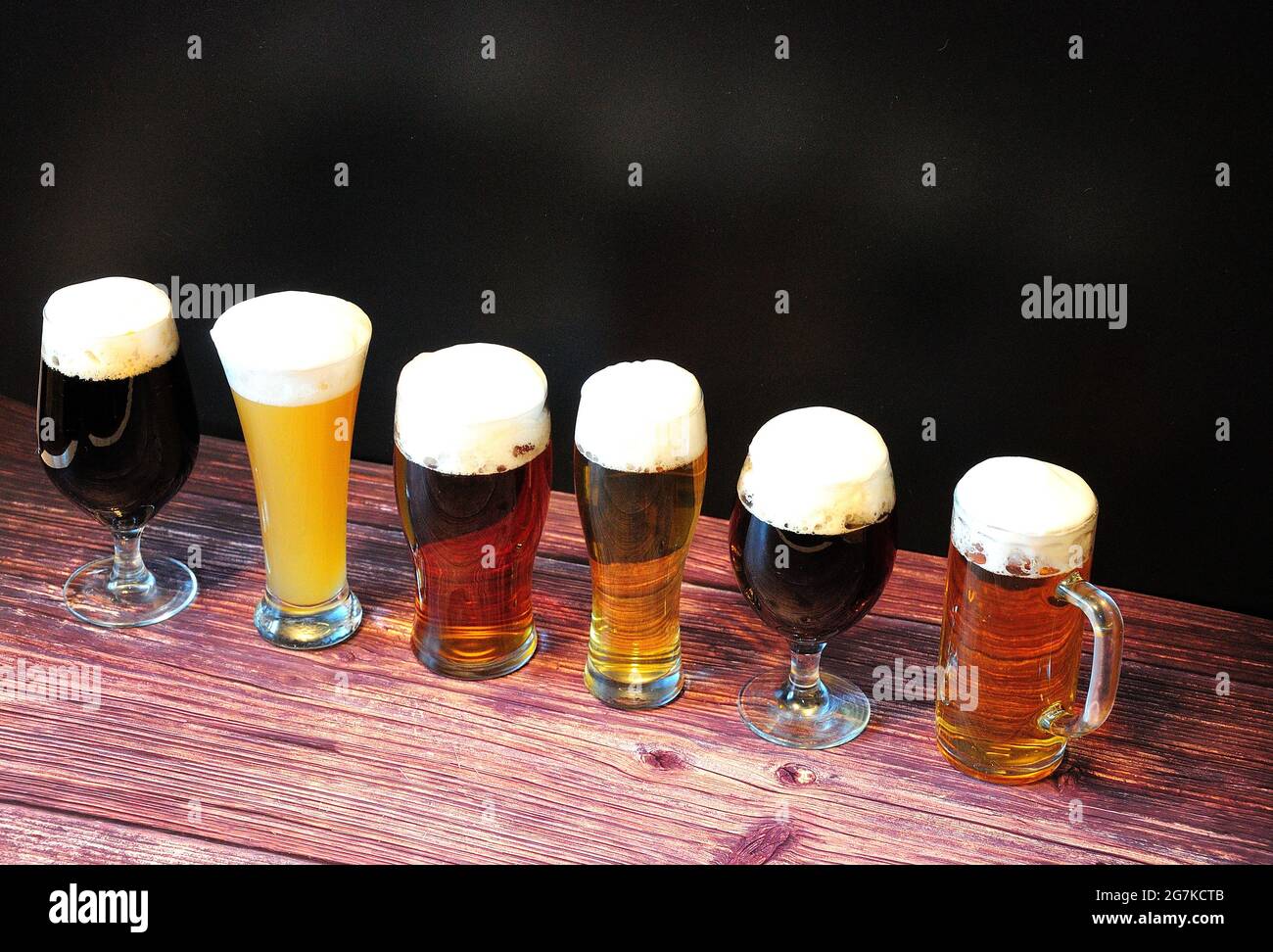 Six verres avec bière de différentes variétés, se tiennent sur une table en bois. Gros plan. Banque D'Images
