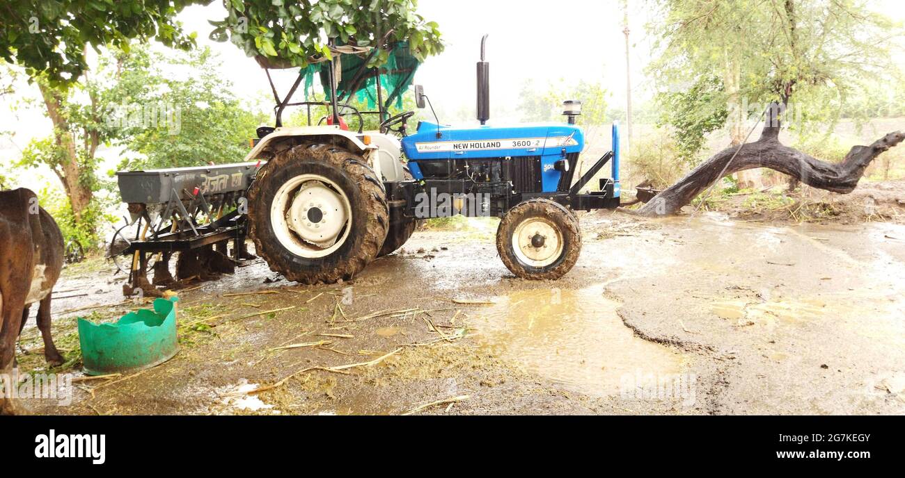 INDORE, INDE - 25 juin 2021 : Indore, madhya pradesh, inde - 25 juin 2021 : un tracteur avec semoir dans le sol, arbres, animaux, etc Banque D'Images