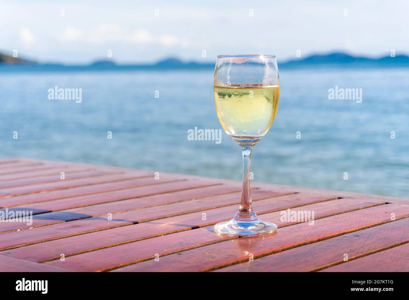 Un verre de vin blanc est placé dans un bar en bord de mer en haute saison. Banque D'Images