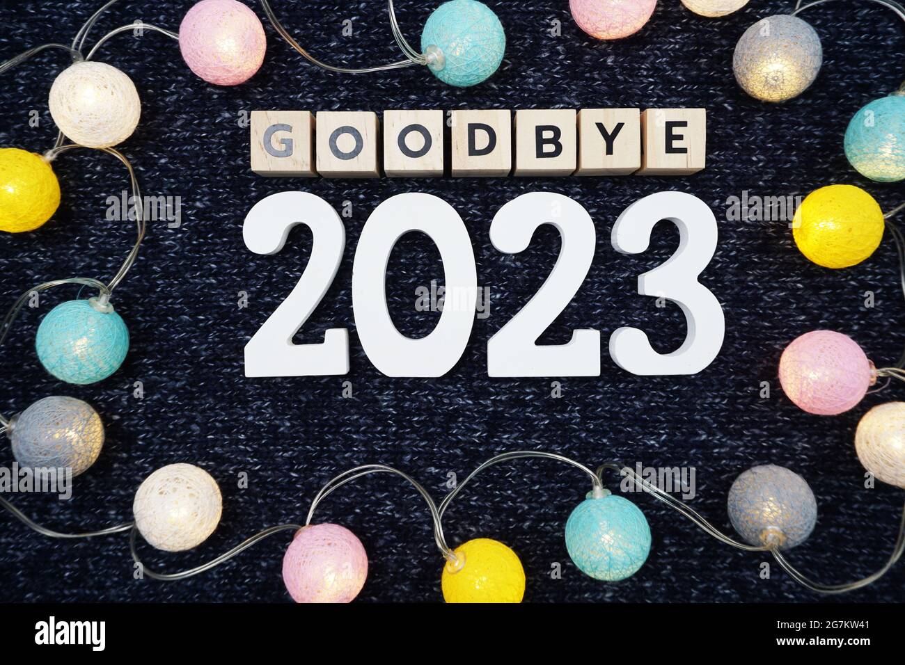 Lettre à l'alphabet Au revoir 2023 avec boule en coton à DEL sur fond de tissu tricoté bleu Banque D'Images