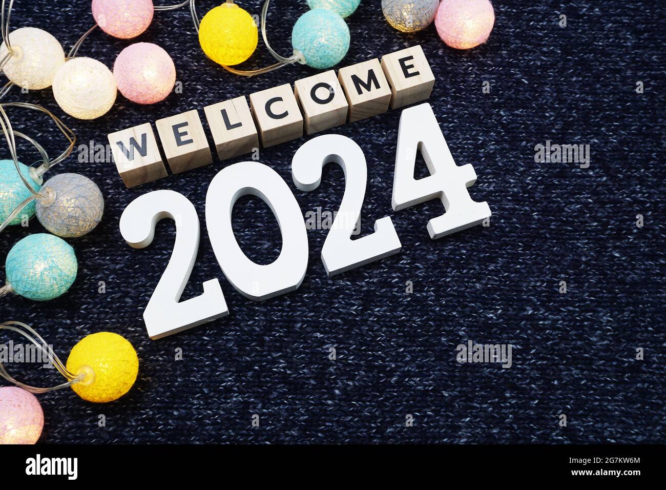 Bienvenue lettre de l'alphabet 2024 avec boule de coton LED sur fond de tissu tricoté bleu Banque D'Images