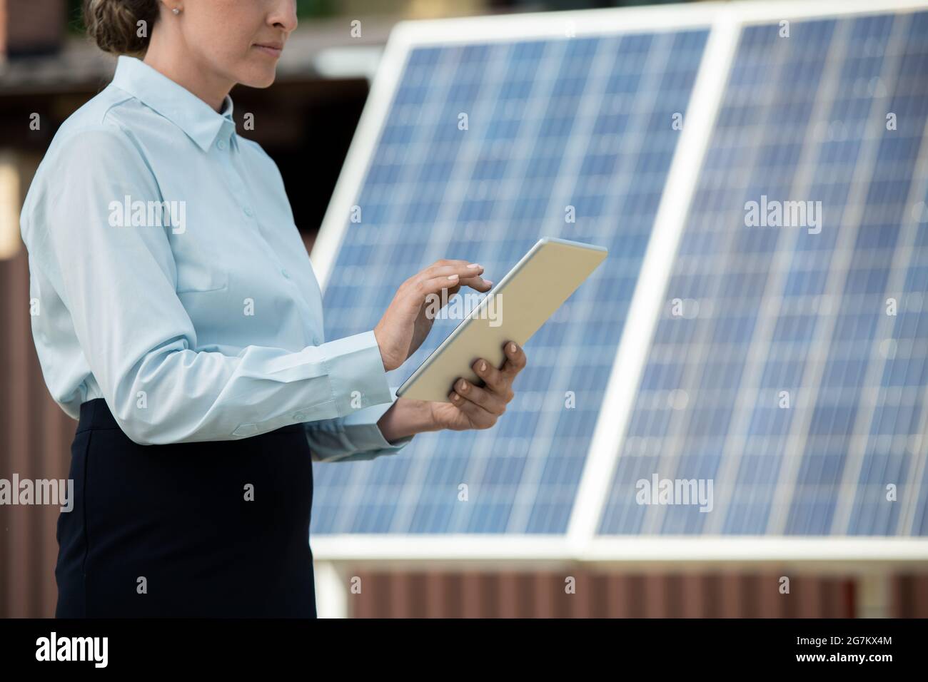 Femme d'affaires travaillant sur un ordinateur tablette en se tenant contre des panneaux photovoltaïques sur la station d'énergie solaire Banque D'Images