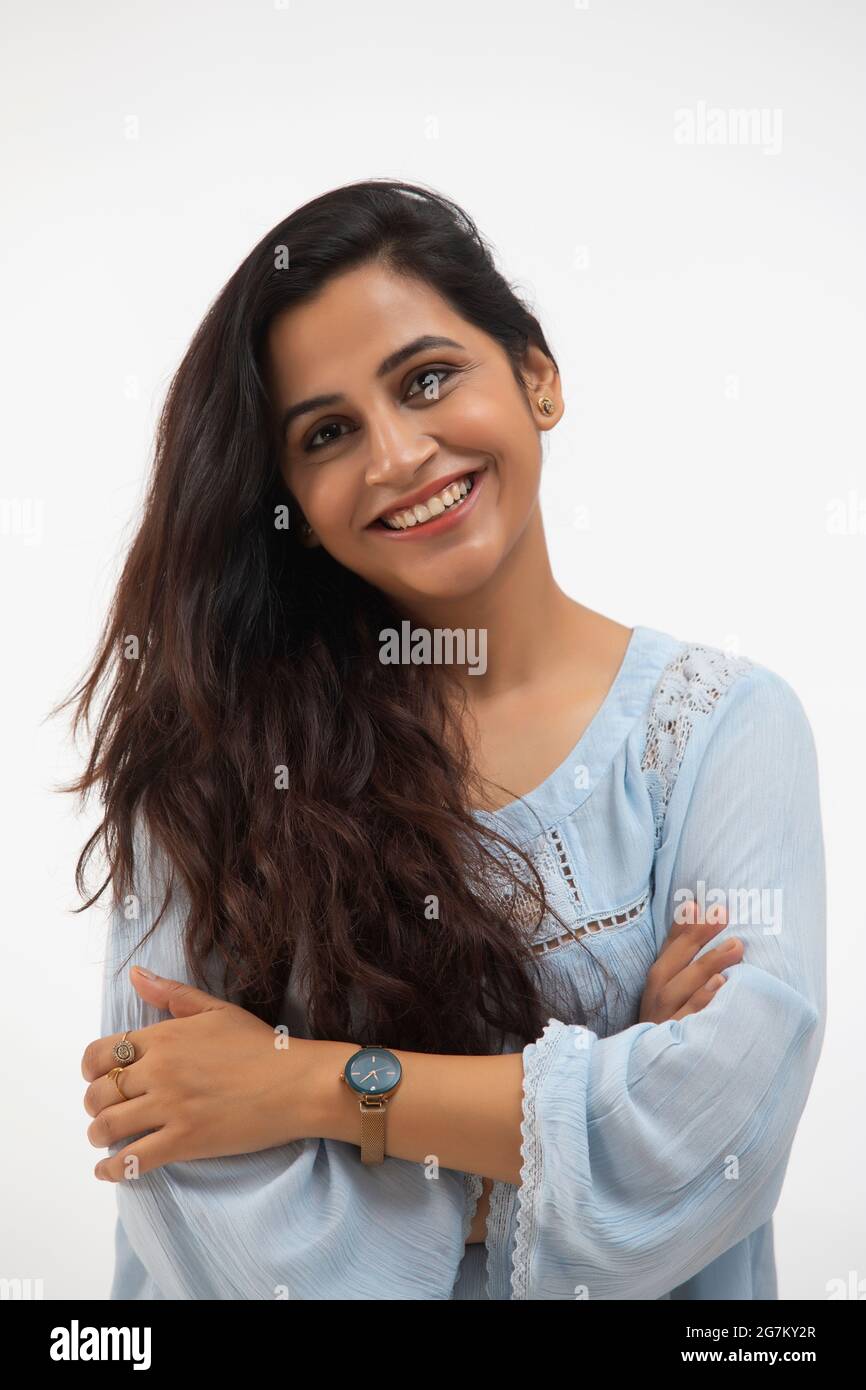 UNE JEUNE FEMME CONFIANTE AUX MAINS PLIÉES SOURIANT À LA CAMÉRA Banque D'Images