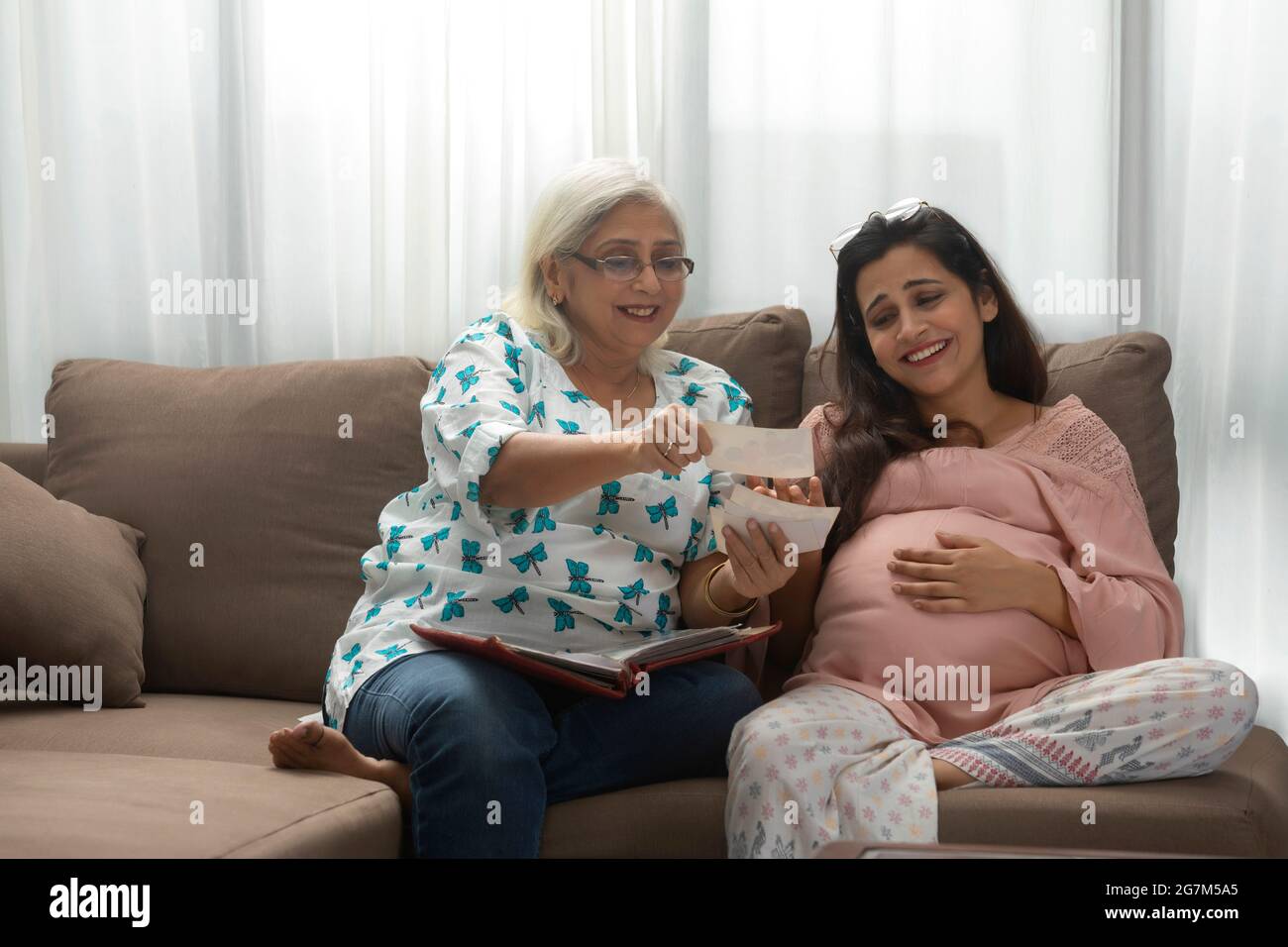 UNE FEMME ADULTE ÂGÉE MONTRANT DE VIEILLES PHOTOS À UNE FILLE ENCEINTE Banque D'Images