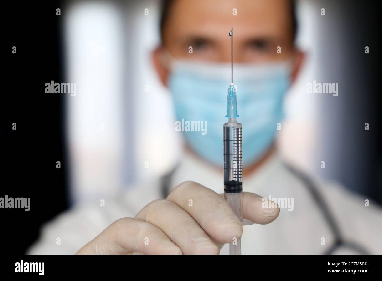 Médecin avec seringue en main, homme dans un masque médical se préparant à l'injection. Concept de vaccination pendant la pandémie de Covid-19 Banque D'Images