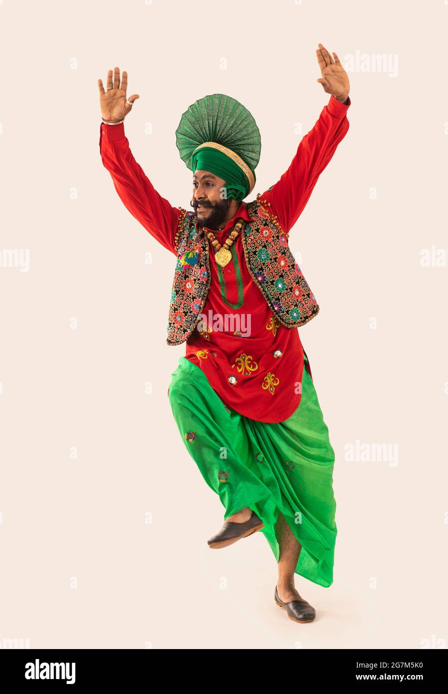 Un danseur Bhangra effectuant une étape de danse avec les mains dans l'air. Banque D'Images