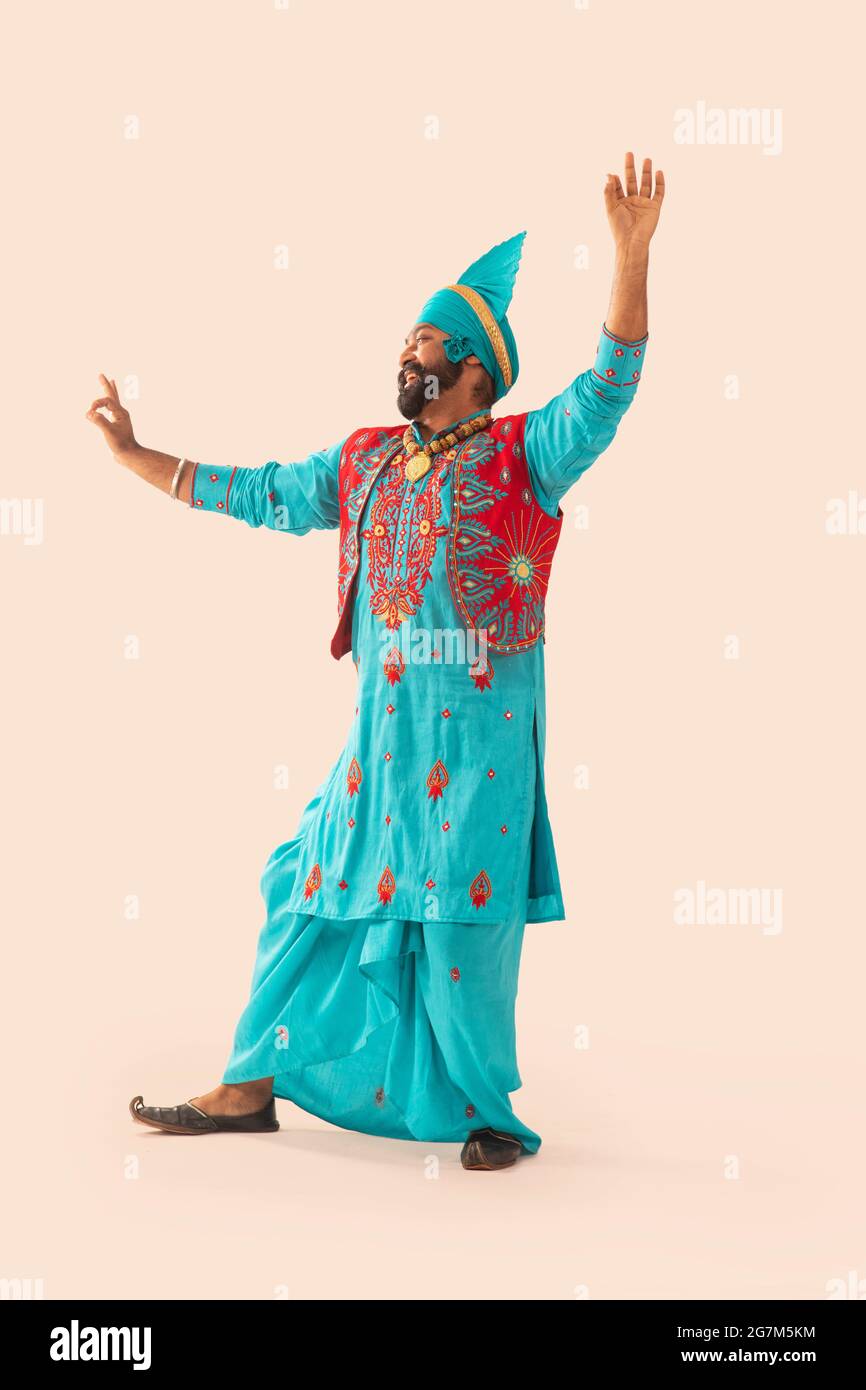 Un danseur Bhangra regardant vers la gauche faisant un pas de danse avec les mains dans l'air. Banque D'Images