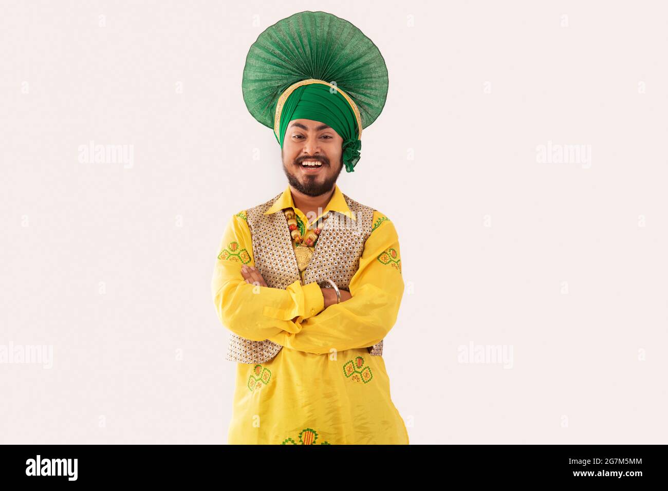 Un homme dans le costume de Bhangra debout heureux avec les bras pliés. Banque D'Images