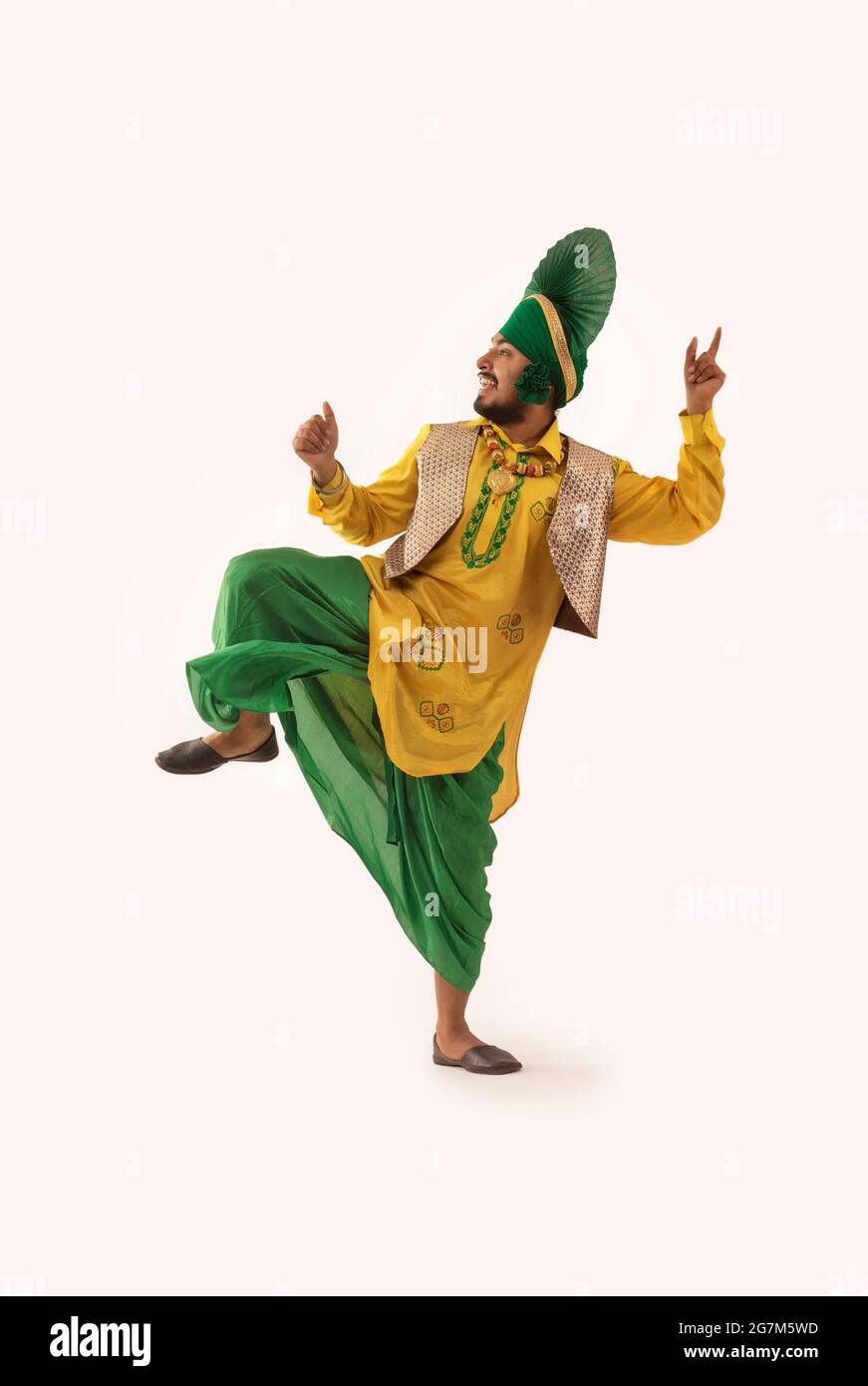 Un danseur Bhangra présentant une étape avec des gestes de main et une jambe soulevée. Banque D'Images