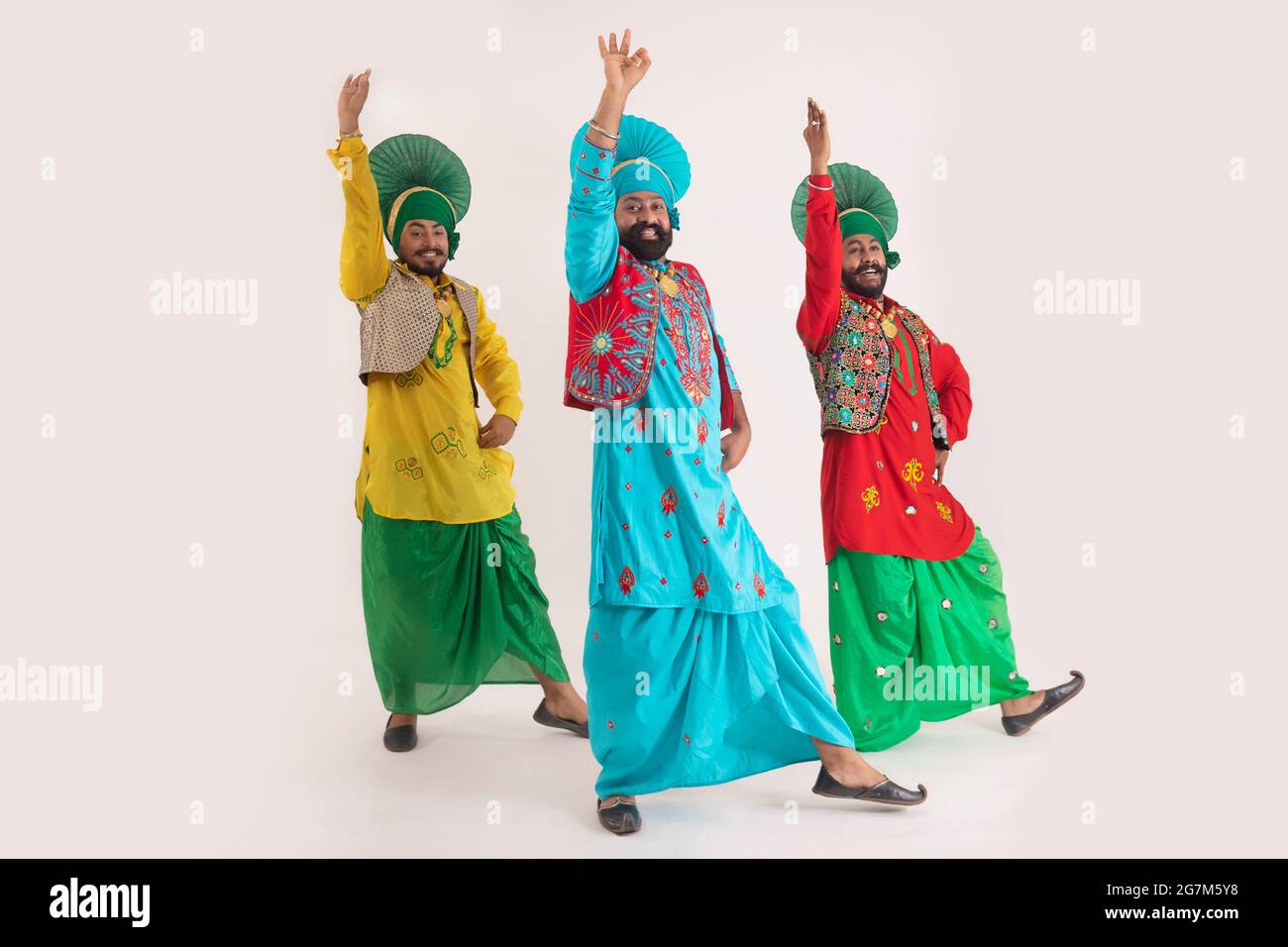 Trois danseurs de Bhangra exécutant un pas de danse avec des gestes de main. Banque D'Images