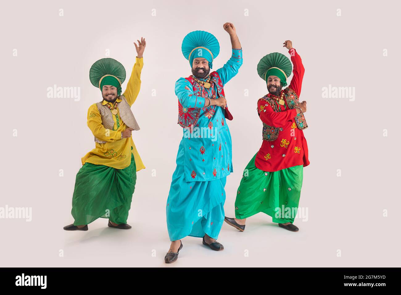 Trois danseurs de Bhangra exécutant un pas de danse avec des gestes de main. Banque D'Images