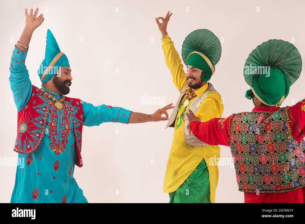Trois danseurs de Bhangra en mouvement exécutant un pas de danse avec des gestes de main. Banque D'Images