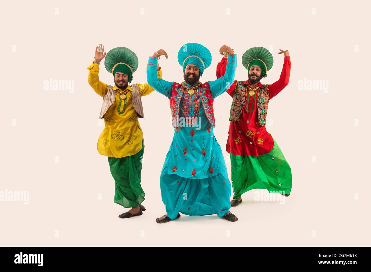 Trois danseurs de Bhangra exécutant un pas de danse avec des gestes de main. Banque D'Images