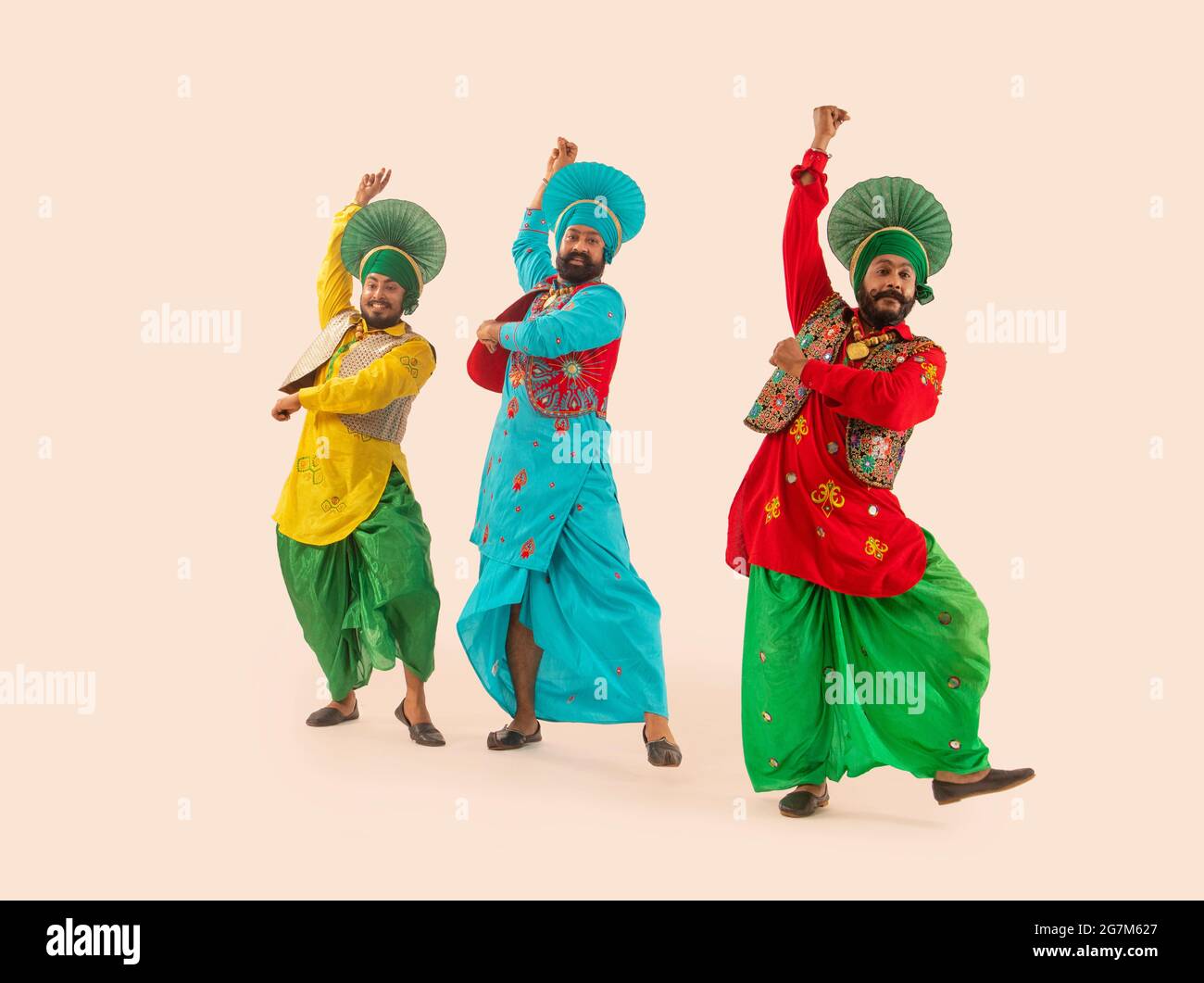 Trois danseurs de Bhangra exécutant un pas de danse avec des gestes de main. Banque D'Images