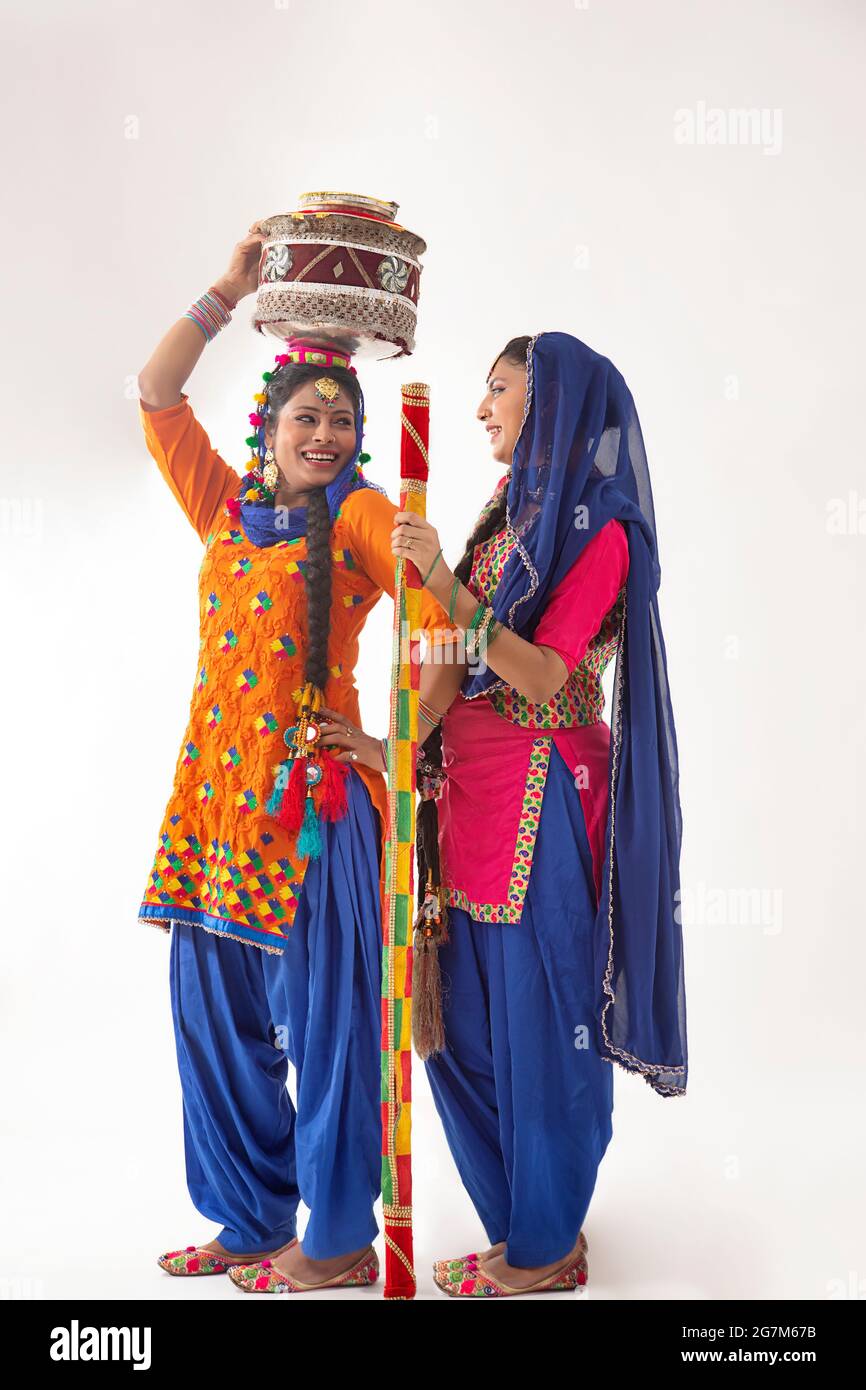 Deux danseurs de Giddha debout ensemble, tenant le matki décoré et le bâton. Banque D'Images