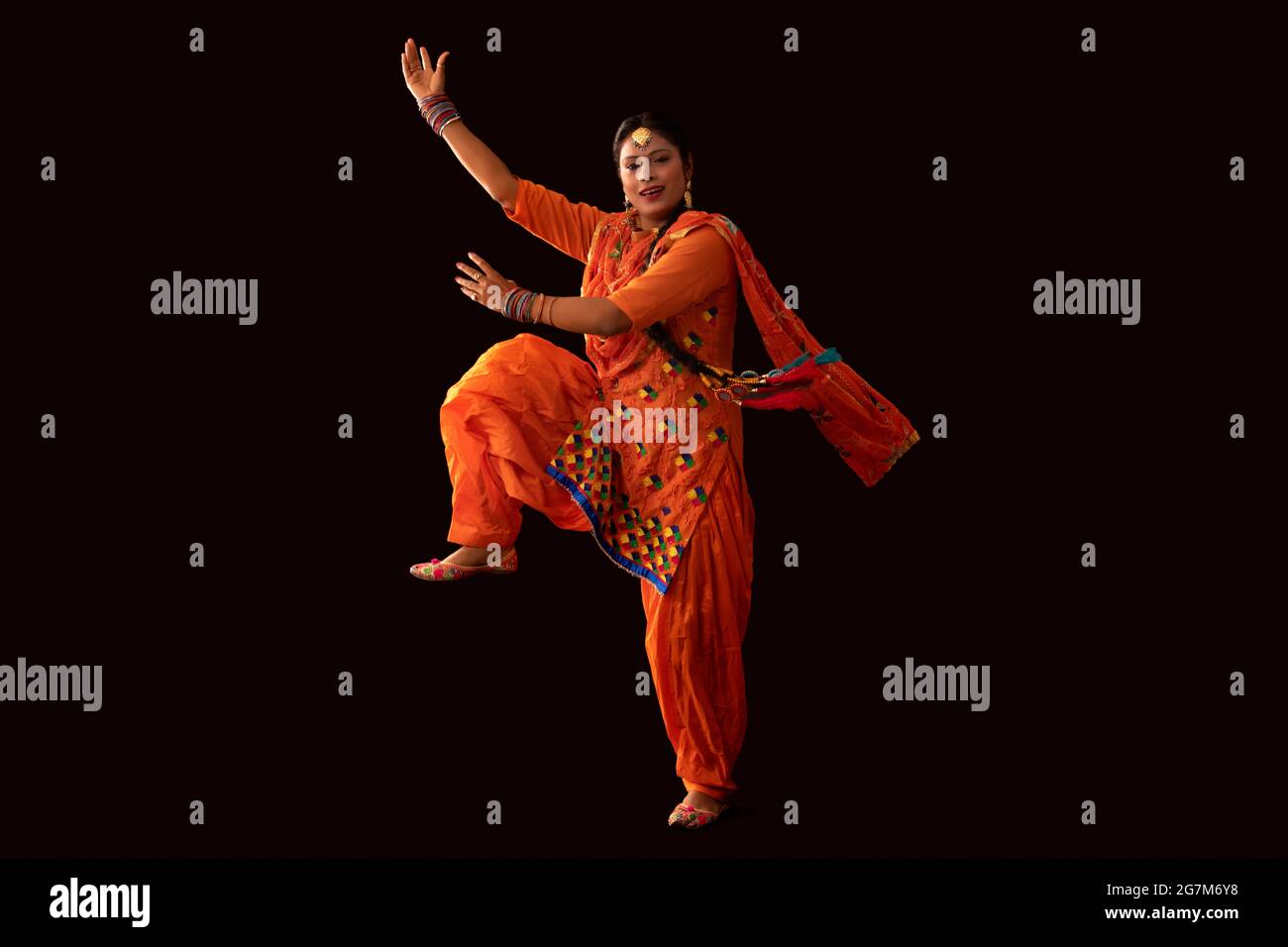 Une femme en costume de Giddha représentant un pas de danse avec les mains et une jambe dans les airs. Banque D'Images