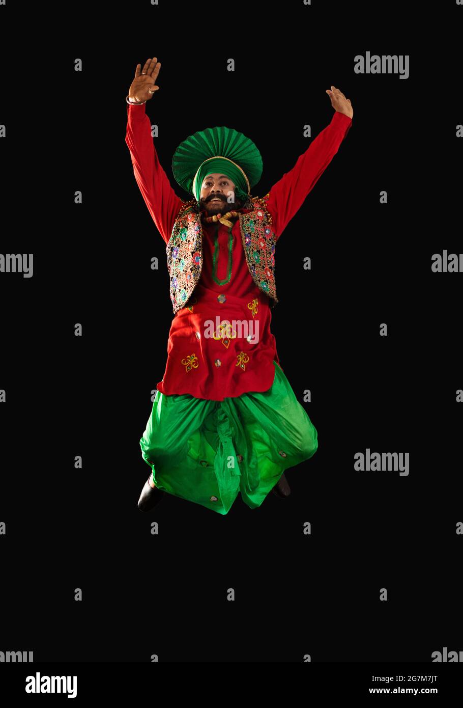 Un danseur de Bhangra sautant avec les mains vers le haut pour effectuer une étape de danse. Banque D'Images