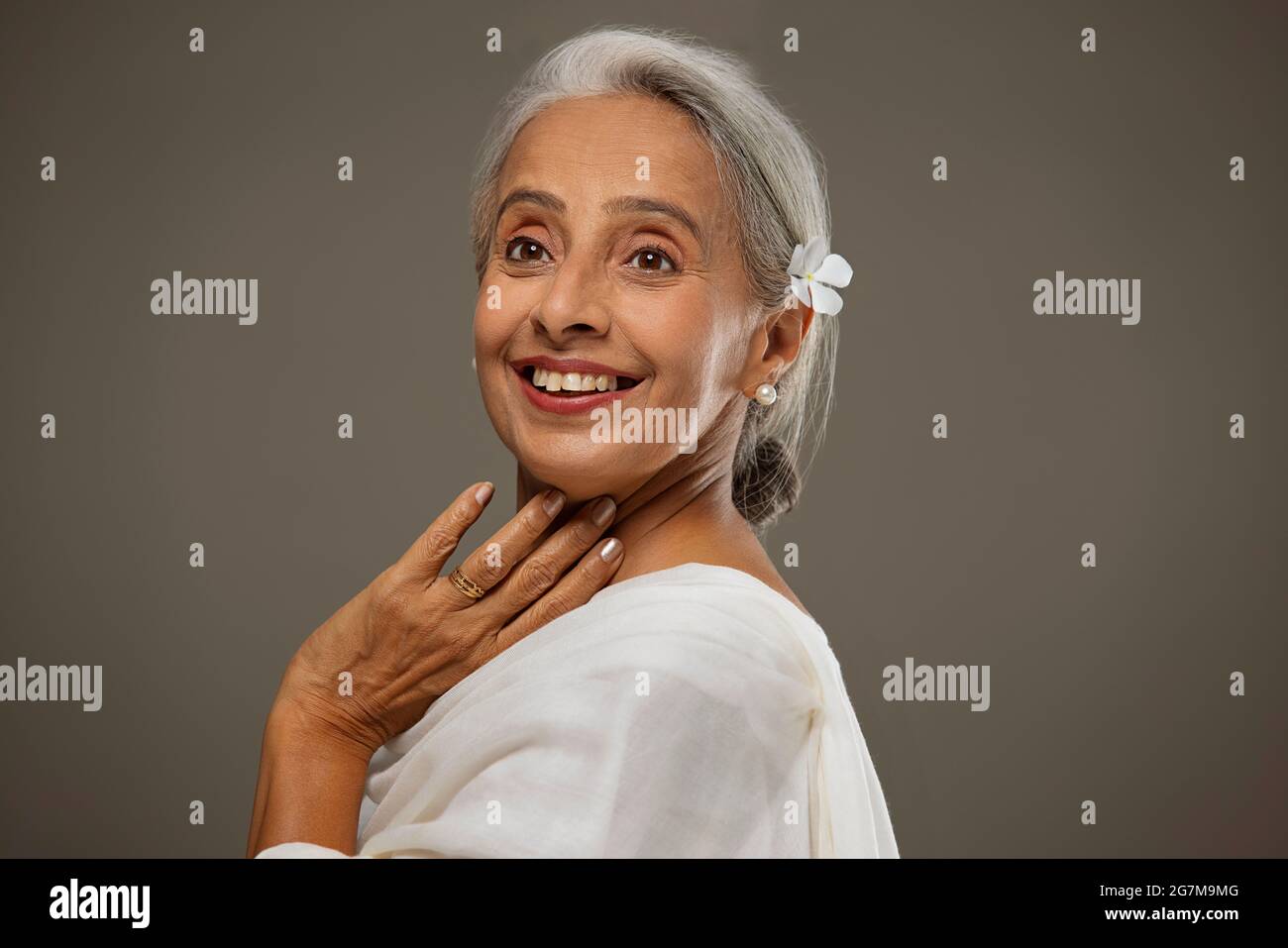 Portrait de la vieille belle femme avec une fleur dans ses cheveux regardant ailleurs. Banque D'Images