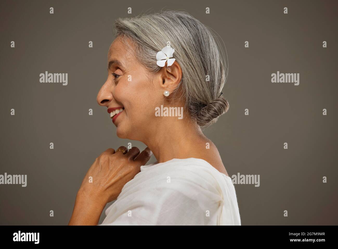 Portrait de la vieille belle femme avec une fleur dans ses cheveux. Banque D'Images