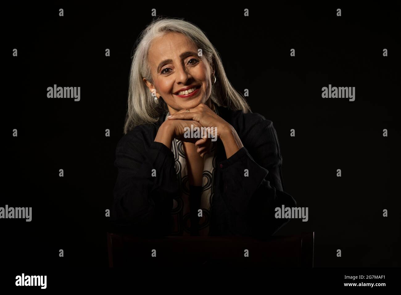 Portrait d'une vieille belle femme avec les mains sous son menton. Banque D'Images
