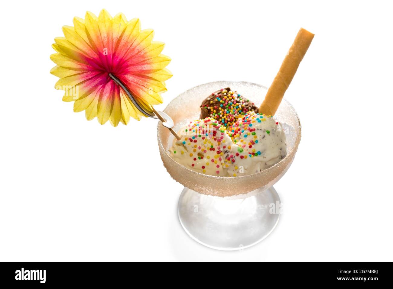 Trois boules de glace aromatisées au chocolat, à la crème et à la vanille avec perles de sucre, galette et fleur de papier dans une tasse de verre, isolées sur blanc Banque D'Images