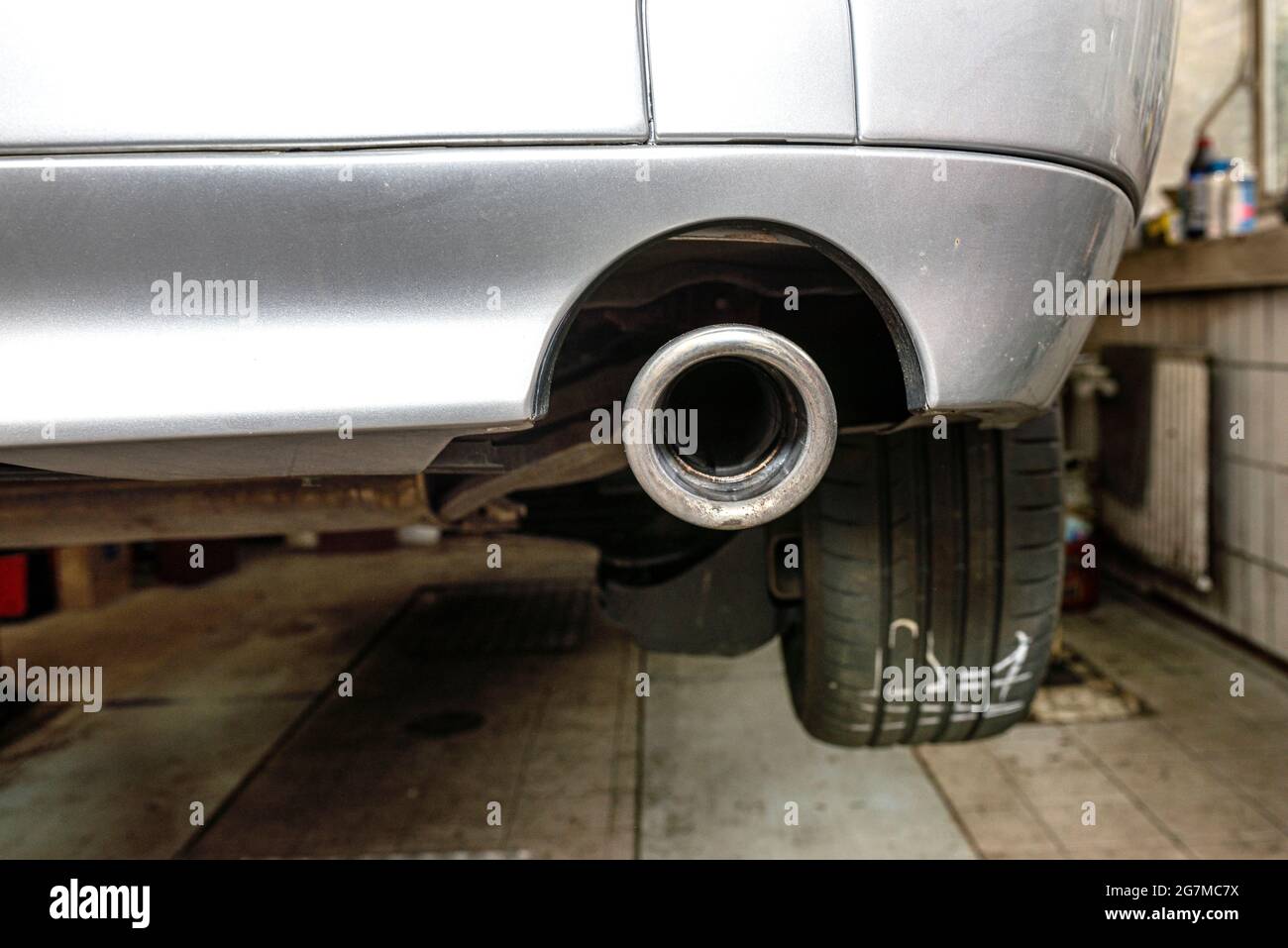 Le système d'échappement dans la voiture vu de dessous, embout d'échappement visible, la voiture est sur l'ascenseur dans l'atelier de voiture. Banque D'Images