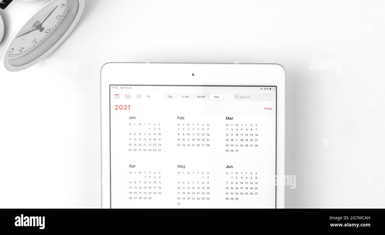 Tablette avec calendrier 2021 ouvert, espace de travail blanc avec réveil, concept commercial Banque D'Images