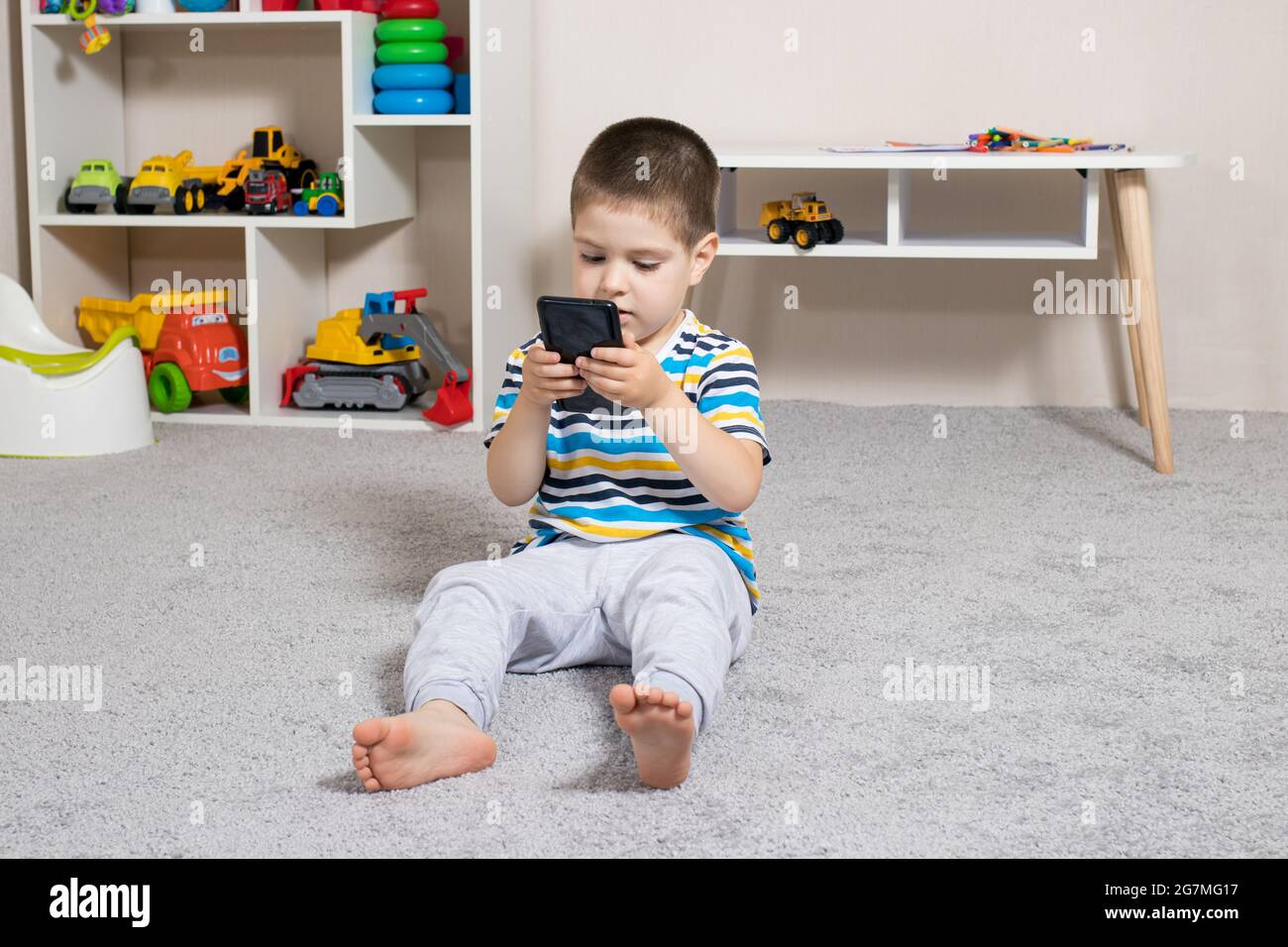 Un Garçon De 3 à 4 Ans Regarde L'écran Du Téléphone.