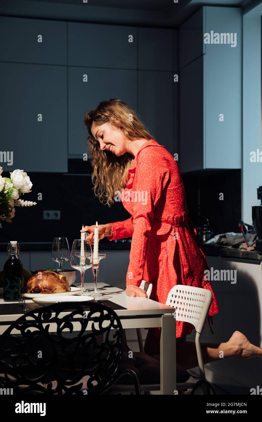 belle femme femme au foyer en robe rouge prépare un dîner romantique aux  chandelles Photo Stock - Alamy