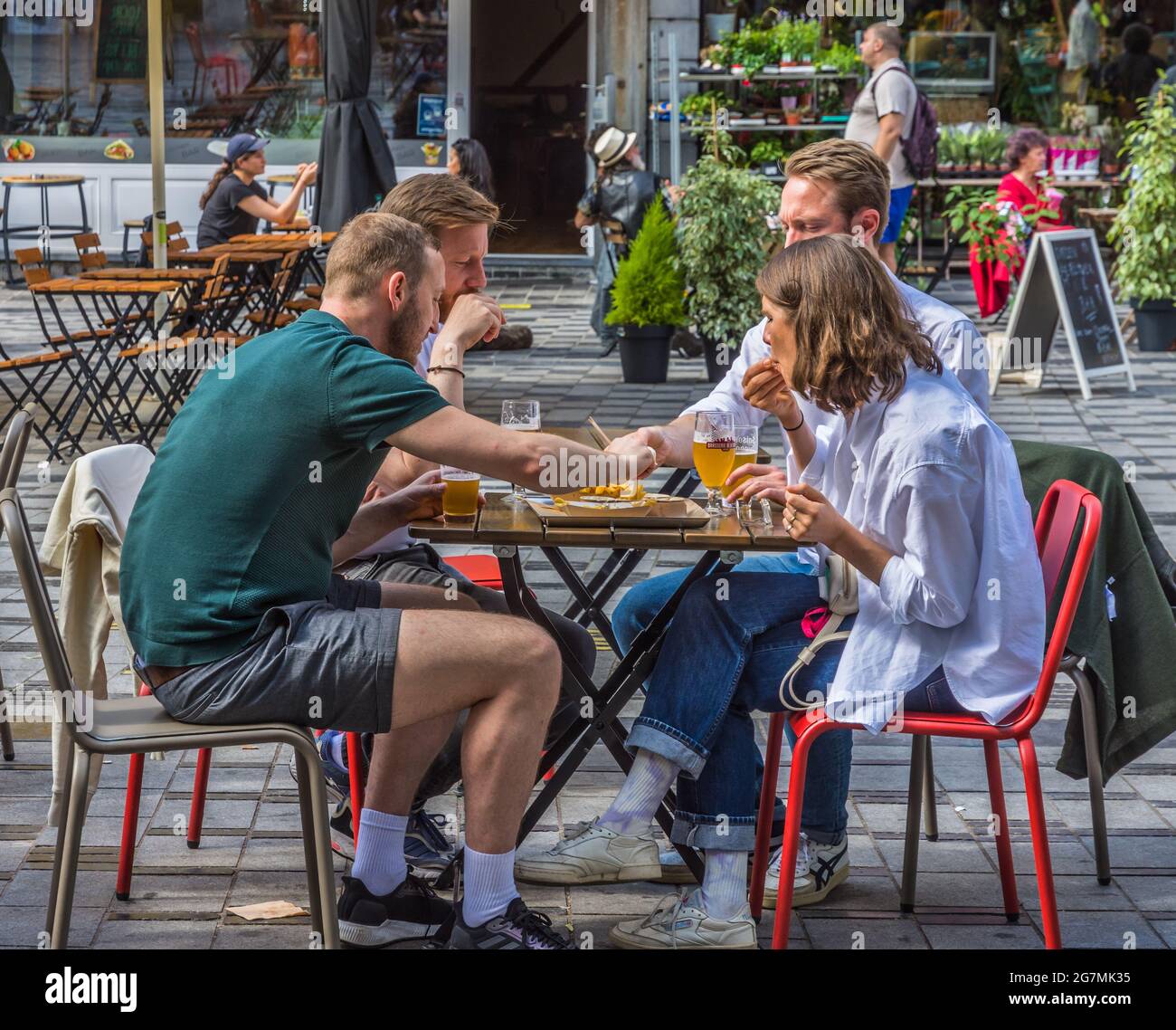 Groupe d'amis mangeant des frites pour le déjeuner sur la terrasse du café restaurant à Saint Gilles, Bruxelles, Belgique. Banque D'Images