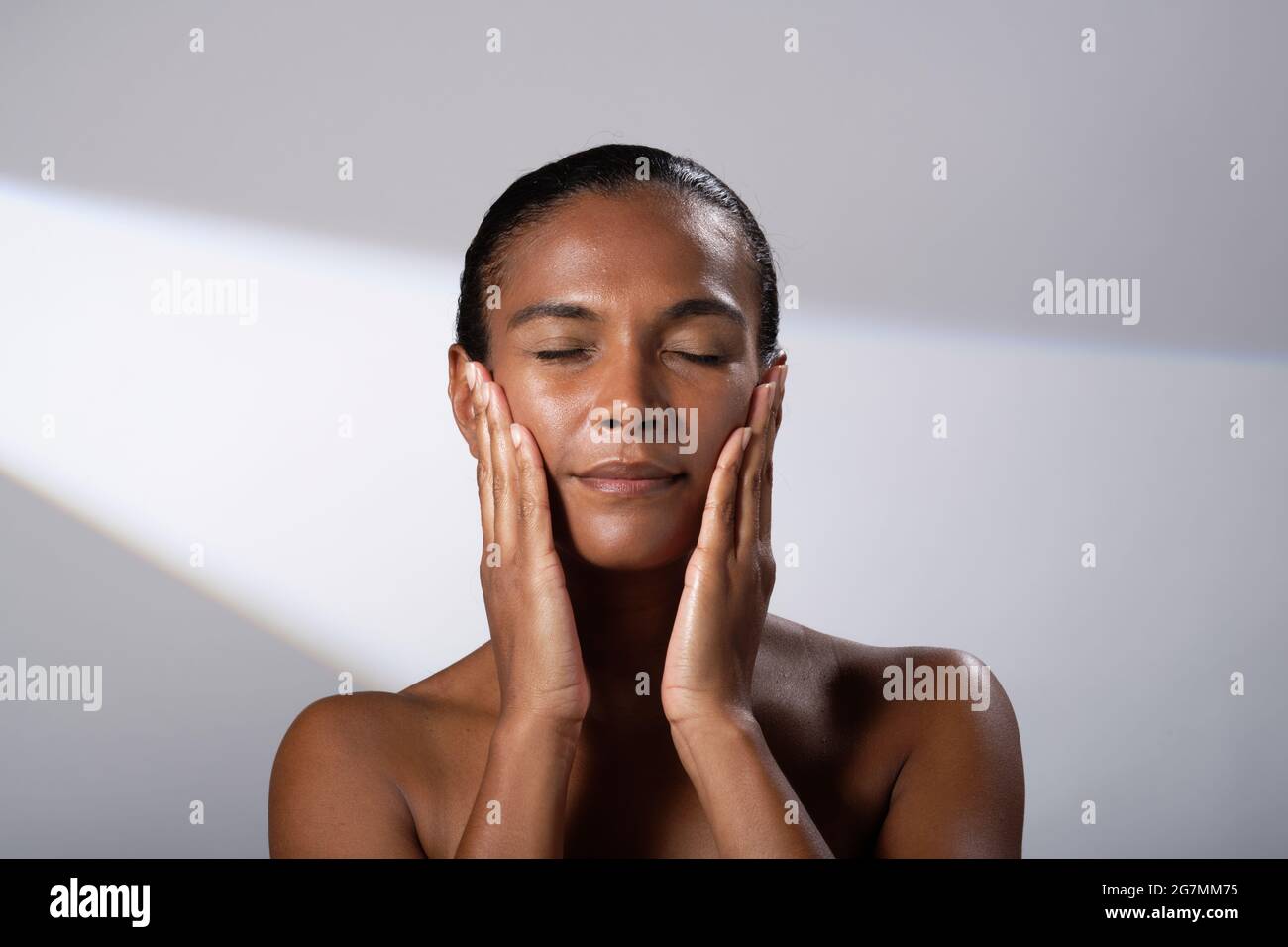 Images de beauté d'une femme avec un ton de peau plus foncé. Images de la tête et de l'épaule de la femme souriante et heureuse. Application de massage du visage/crème. Banque D'Images