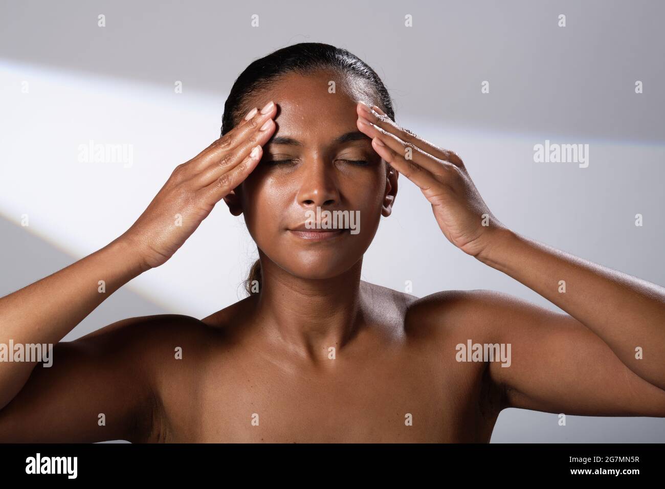 Images de beauté d'une femme avec un ton de peau plus foncé. Images de la tête et de l'épaule de la femme souriante et heureuse. Application de massage du visage/crème. Banque D'Images