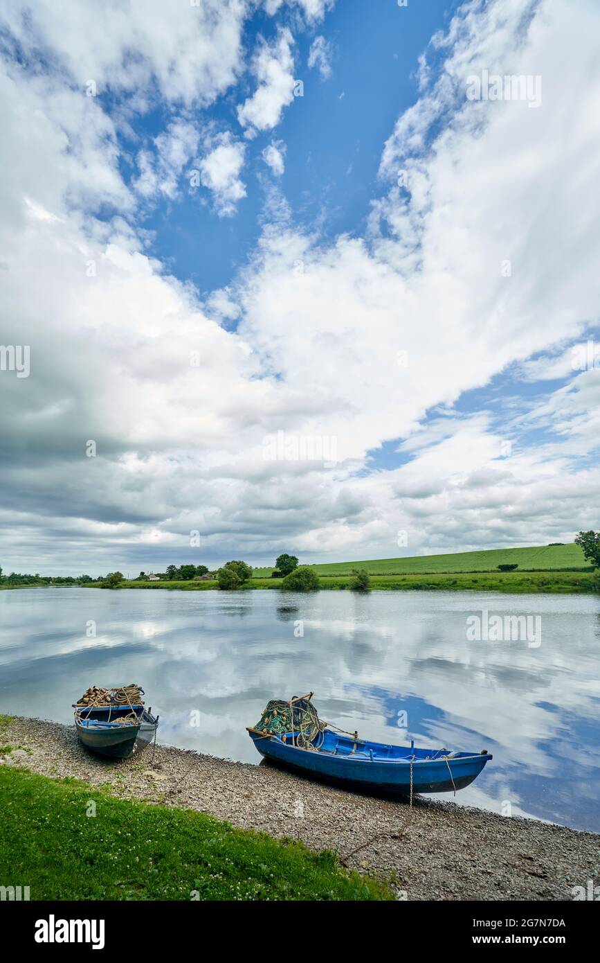 Des bateaux à filets de saumon sur la rivière Tweed à Paxton, dans les frontières écossaises, lors d'une journée d'été ensoleillée avec des reflets étonnants du ciel dans la rivière. Banque D'Images